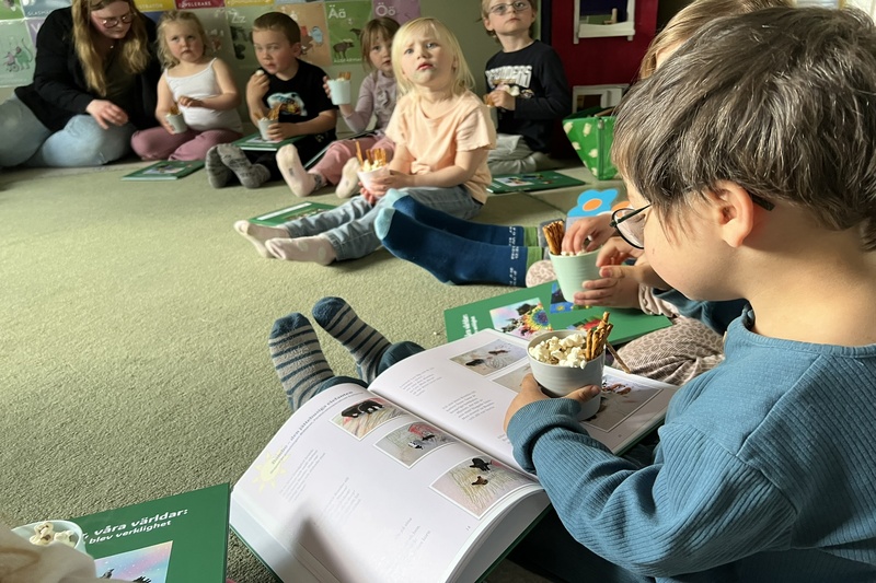 Barn läser i boken och äter popcorn