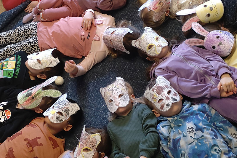 Barn med egenmålade maskar på ansiktet ligger i ring på golvet