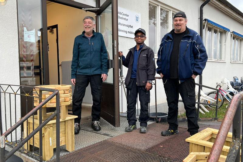 Tre män står på en trappa, en håller upp dörren, välkommen till oss